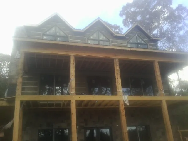 Dormers and porch framing on a large log home under construction — Roof Coating work by our crew in Creston