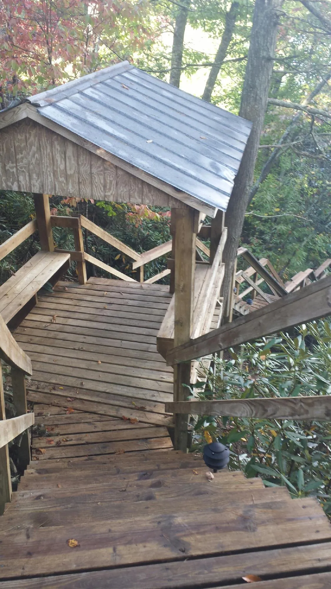 Metal roofed shelter over wooden steps on a wooded walkway — Skylight Repair & Installation work by our crew in Creston